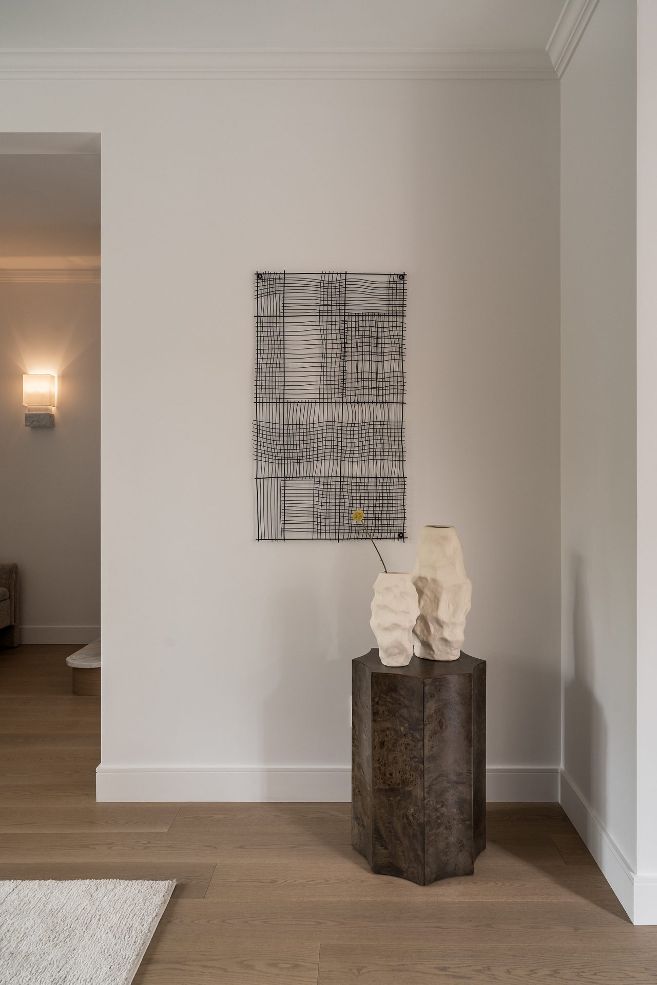 A quiet entryway with woven wall art and ceramic vases on a dark wood console